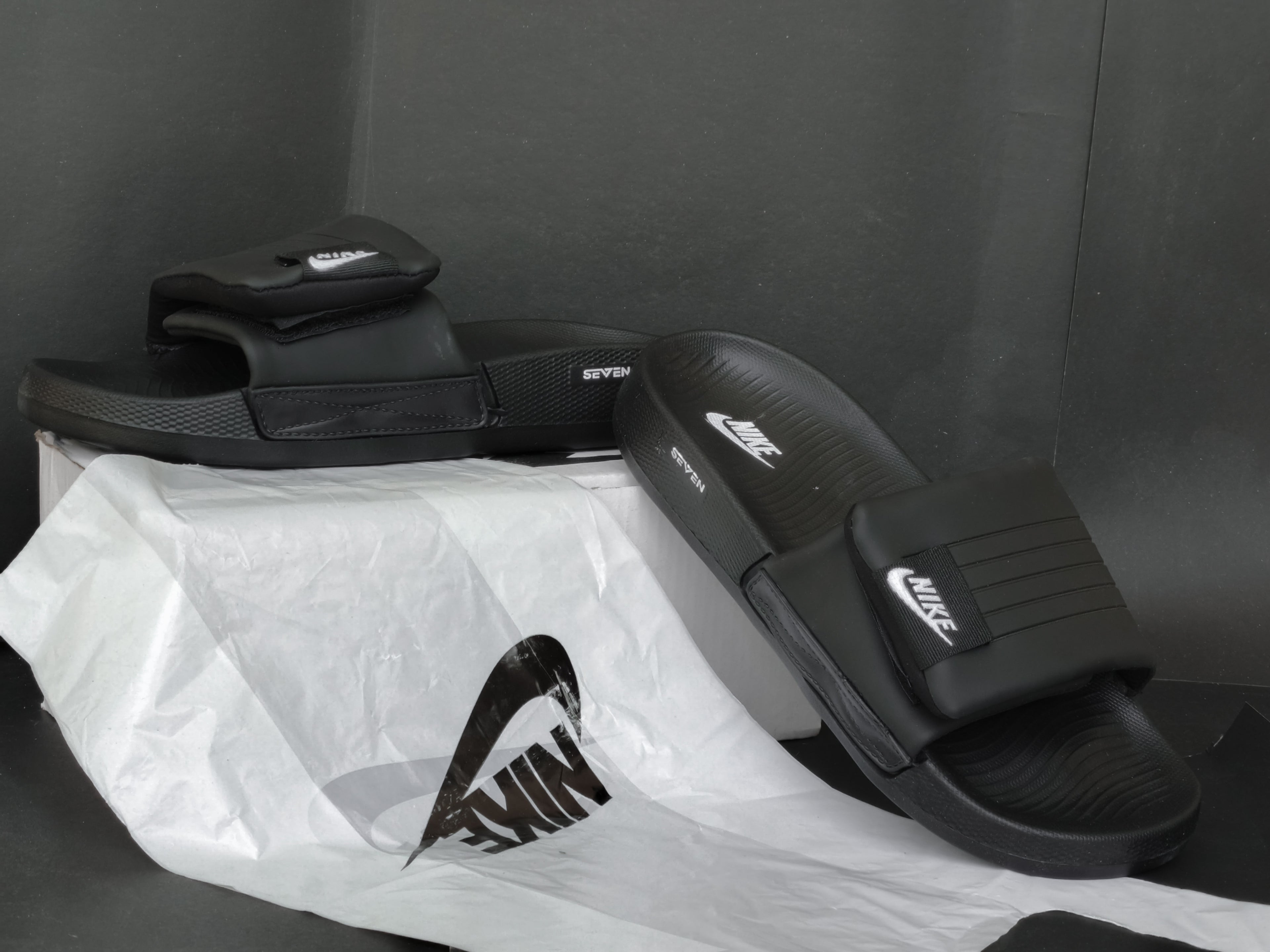 Black Nike slides on a white plastic bag with a dark background