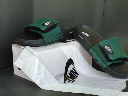 Green and black slides with Nike logo on a white box against a dark background